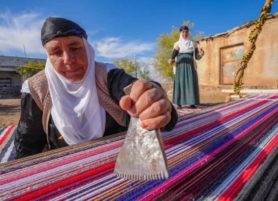 Evinin bah&ccedil;esindeki tezgahta asırlık y&ouml;ntemle kilim dokuyor